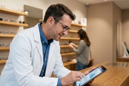 Opticien consultant une plateforme partenaire en ligne dans sa boutique d'optique moderne
